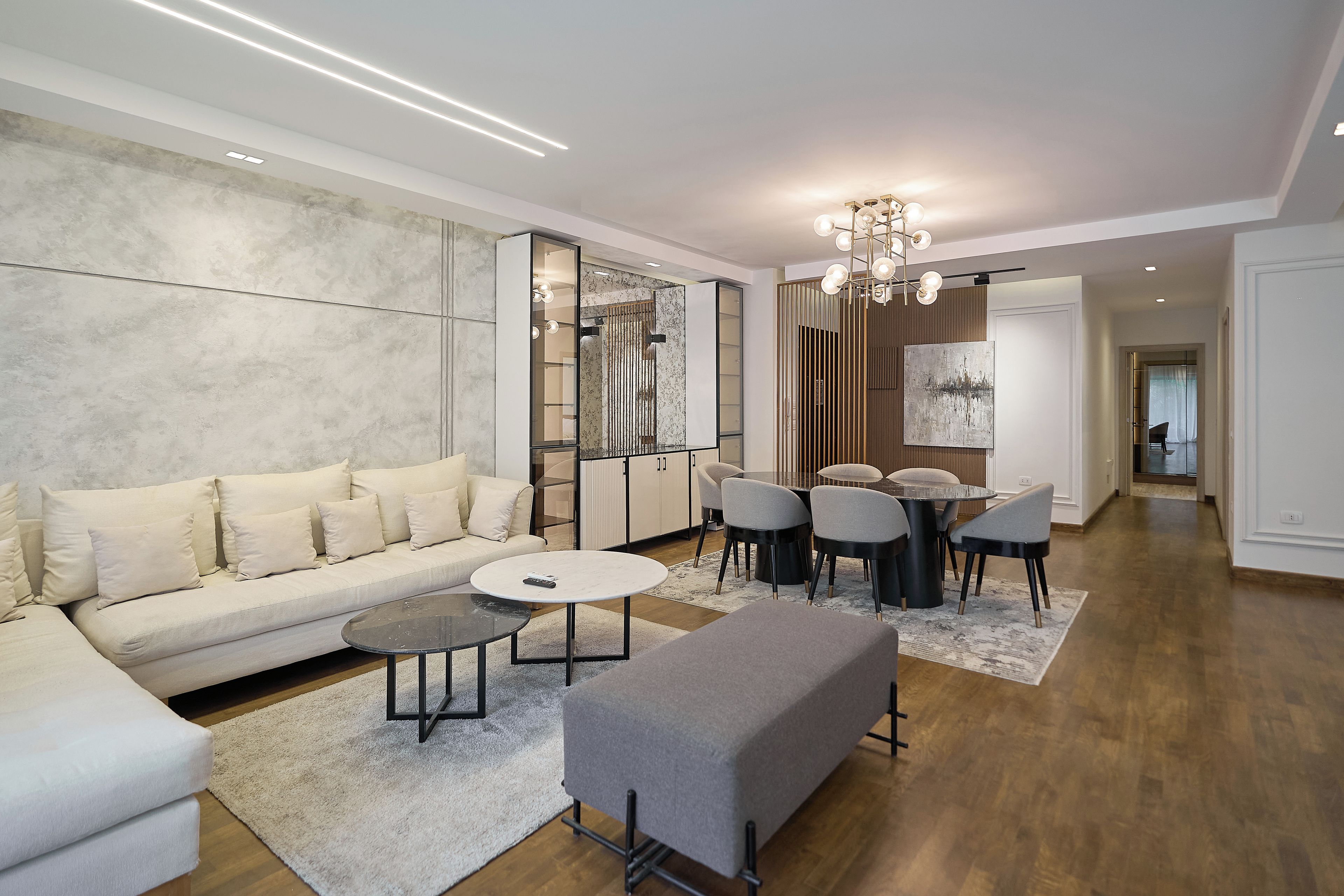 Una sala moderna con sofá, mesa de centro, reposapiés y comedor con sillas y una mesa.