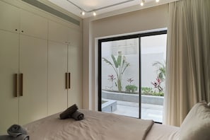 Un dormitorio con una cama grande, un armario y vistas a un balcón con plantas.