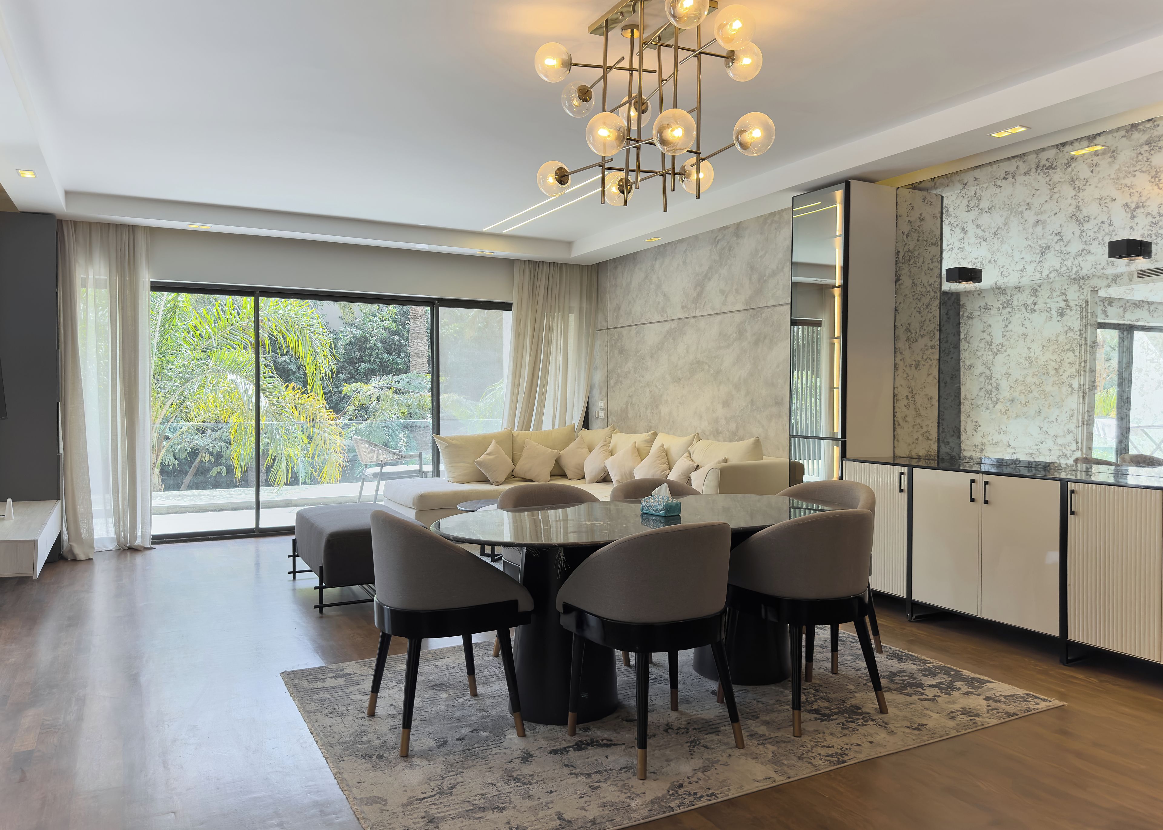 A modern dining area with a round table, chairs, and a sofa.