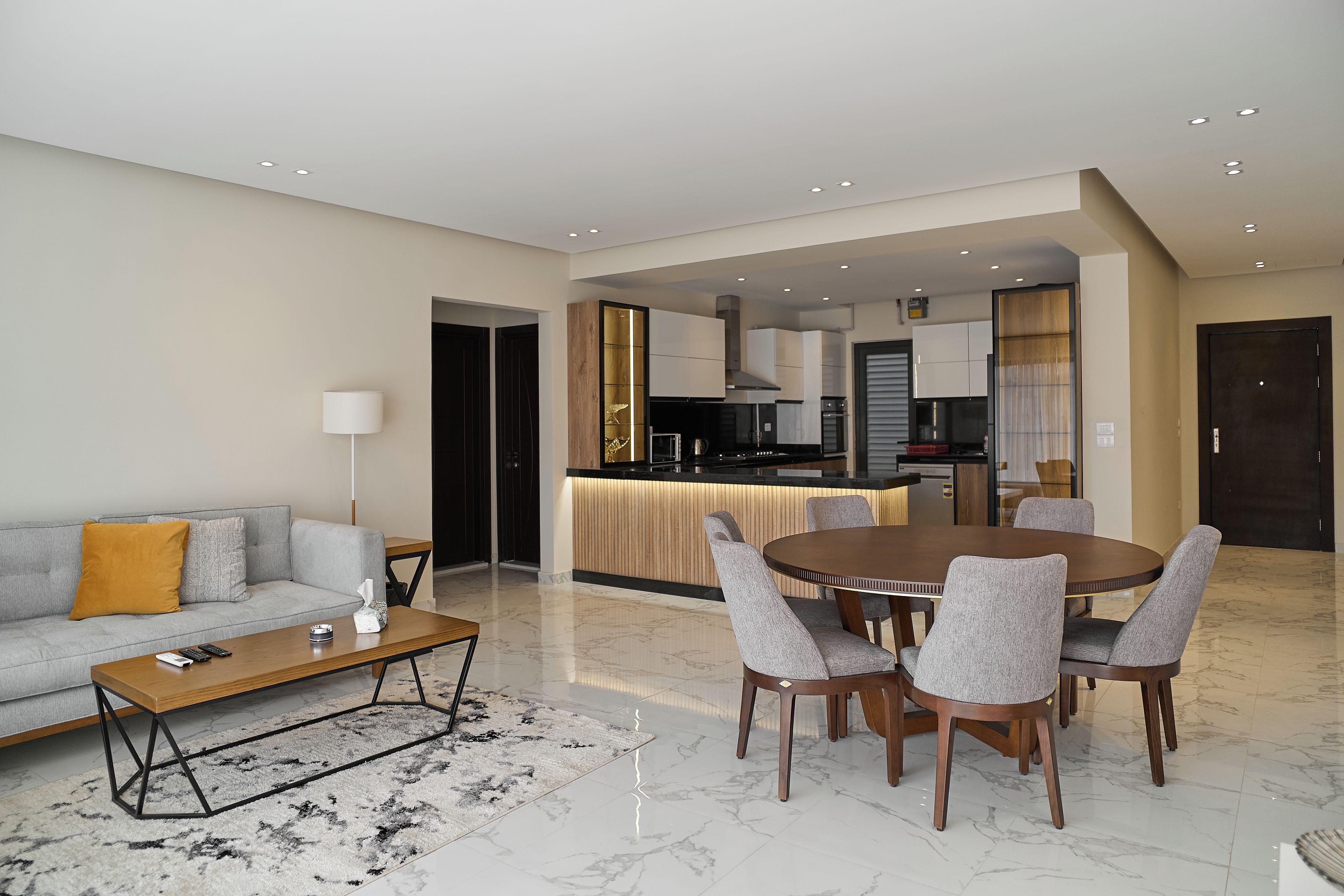 A modern living room with a sofa, coffee table, and dining area with chairs.