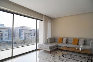 Una sala de estar moderna con un amplio ventanal, un sofá seccional gris y una mesa de centro.