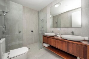 A modern bathroom with a glass-enclosed shower, two sinks, and a large mirror. - Ocean Views Private Villa (Townsville)