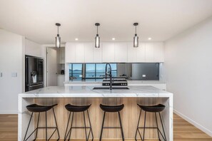 A modern kitchen with a large island, stainless steel appliances, and a view of the outdoors. - Ocean Views Private Villa (Townsville)
