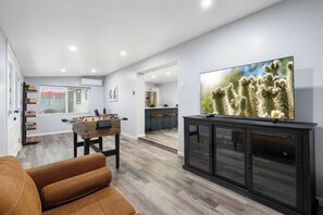 Ein modernes Wohnzimmer mit einem Tischkicker, einem Fernseher und einer Couch.