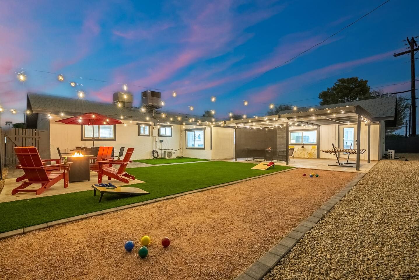 A backyard with a patio, outdoor seating, and a lawn.