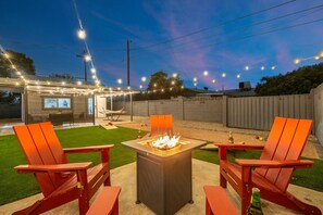 Eine Terrasse im Freien mit Feuerstelle, zwei Stühlen und einem Tisch.