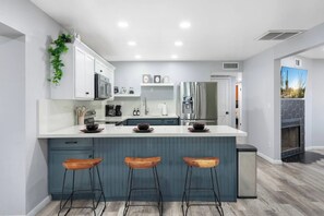 Una cocina moderna con una isla central, taburetes de bar y estufa integrada.