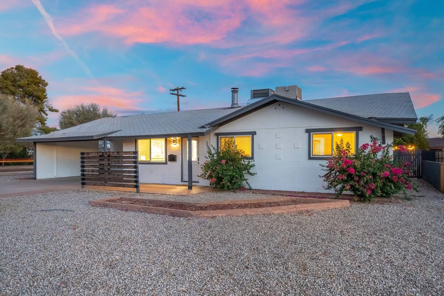A single-story house with a garage, a covered porch, and a gravel driveway.