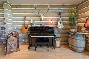 L'intérieur d'une cabane en rondins, avec un grand piano, des guitares et un décor rustique.