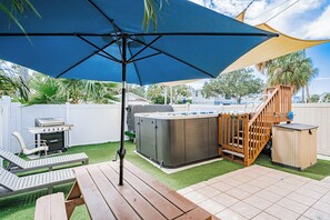 Ein Garten mit Whirlpool, Grill und einer Holzterrasse.