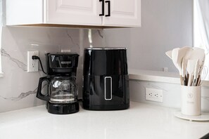 Eine Küche mit Kaffeemaschine, Glasbehälter und weißer Arbeitsplatte.
