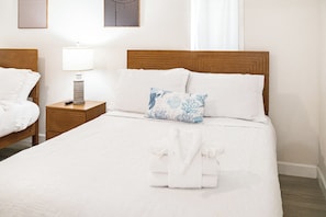 Ein Hotelzimmer mit einem großen Bett, einem Nachttisch mit Lampe und einer Wand mit zwei gerahmten Bildern.