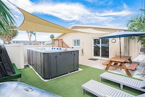 Ein Garten mit Whirlpool, einem Holztisch und einer überdachten Sitzgelegenheit.