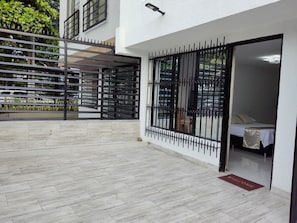 A hotel entrance with a metal gate, a bed with a white cover, and a welcome mat.