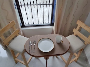 A dining area with a round table, two chairs, a plate, a cup, and cutlery.