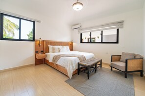 A modern bedroom with a wooden bed, bedside tables, a bench, and a chair. - Artiora Spacious 10-bedroom Villa with Large Jacuzzi & Pool (Sosúa)
