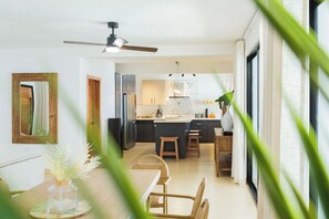 A modern kitchen with a central island, a dining area with wooden furniture, and a large window with natural light. - Artiora Spacious 10-bedroom Villa with Large Jacuzzi & Pool (Sosúa)
