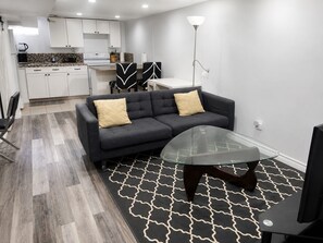 A modern living room with a sofa, a glass coffee table, and a patterned rug.