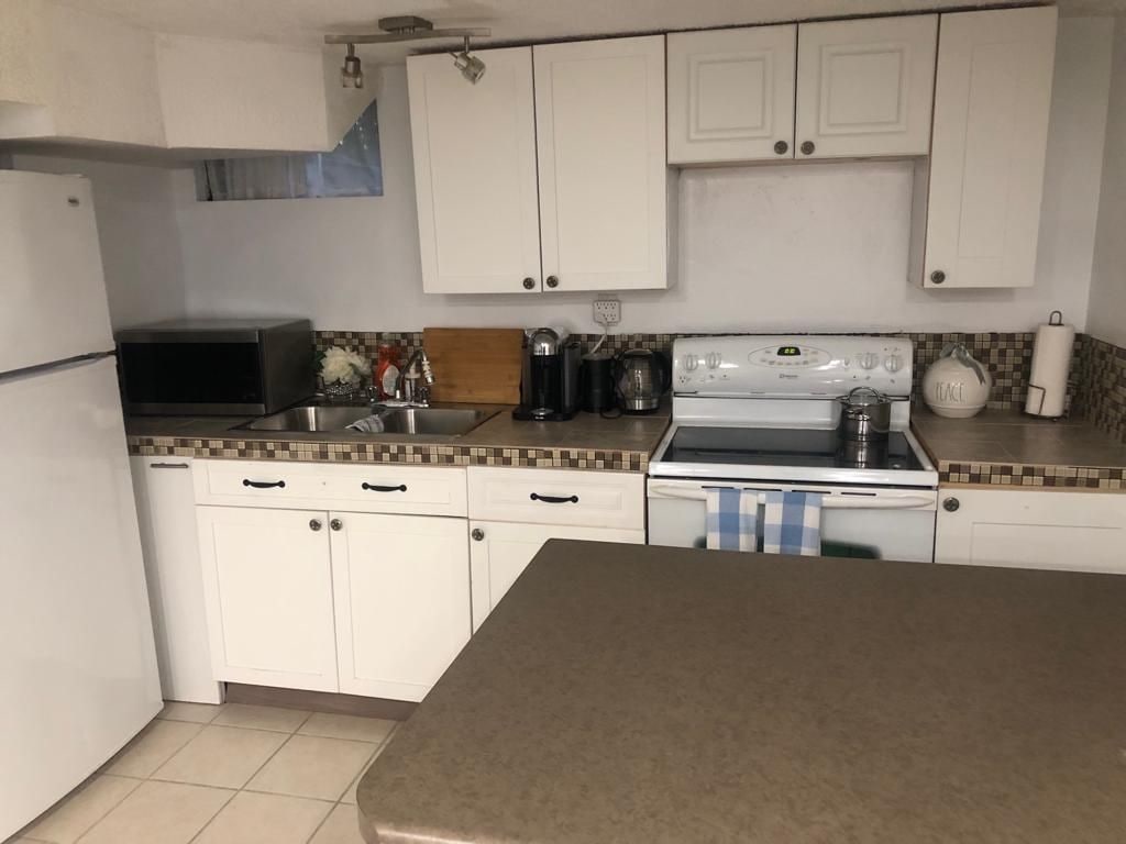 A kitchen with white cabinets, a microwave, a stove, and a sink.