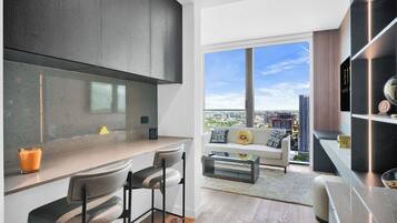 A modern kitchen with a large window, a dining area with a sofa and chairs, and a view of the cityscape.