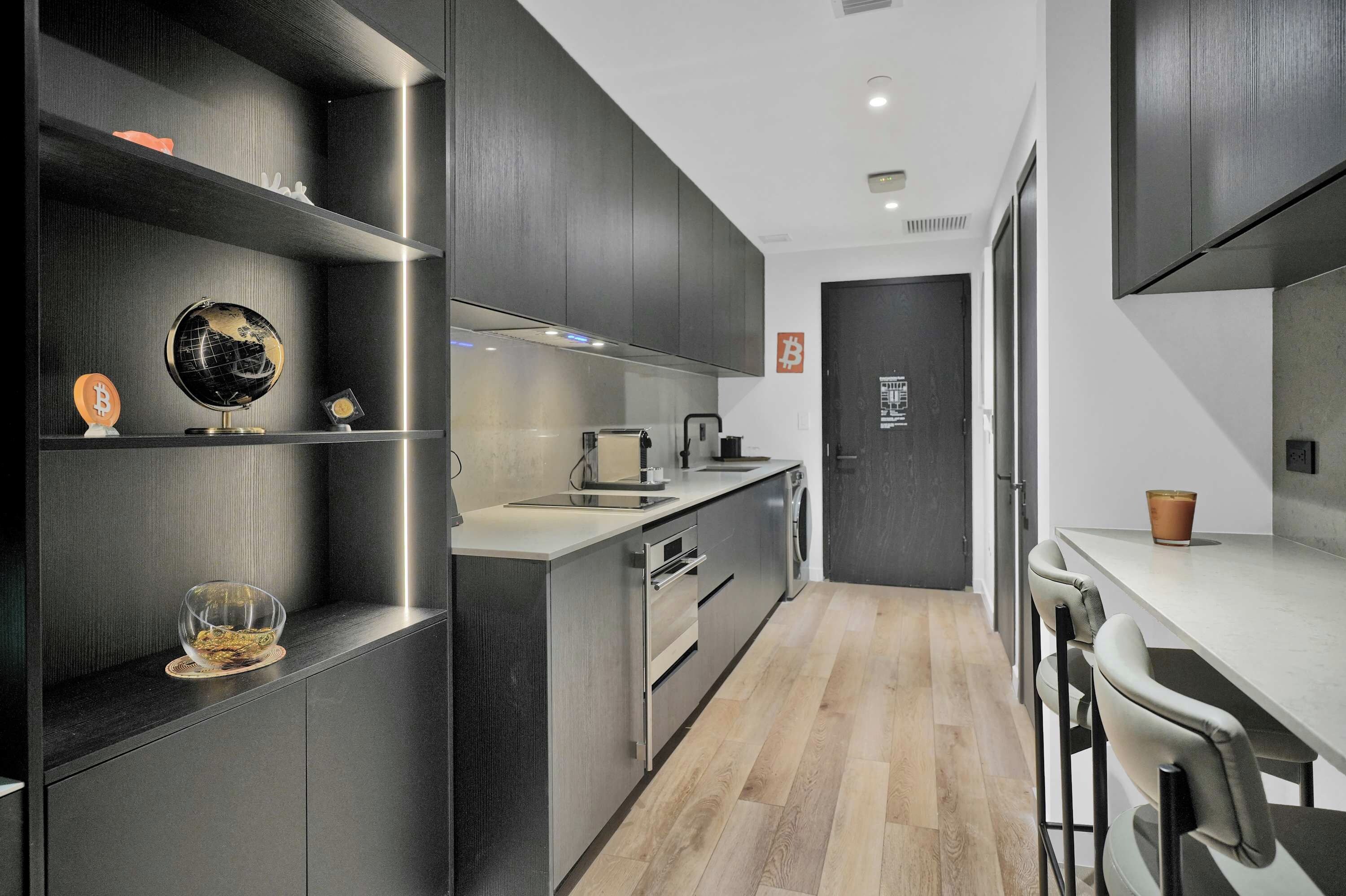 Een moderne keuken met donkere kastjes, een centraal eiland en een minimalistisch design.