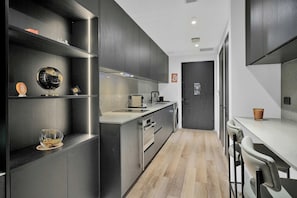 Cuina moderna amb armaris foscos, una illa central i un disseny minimalista.