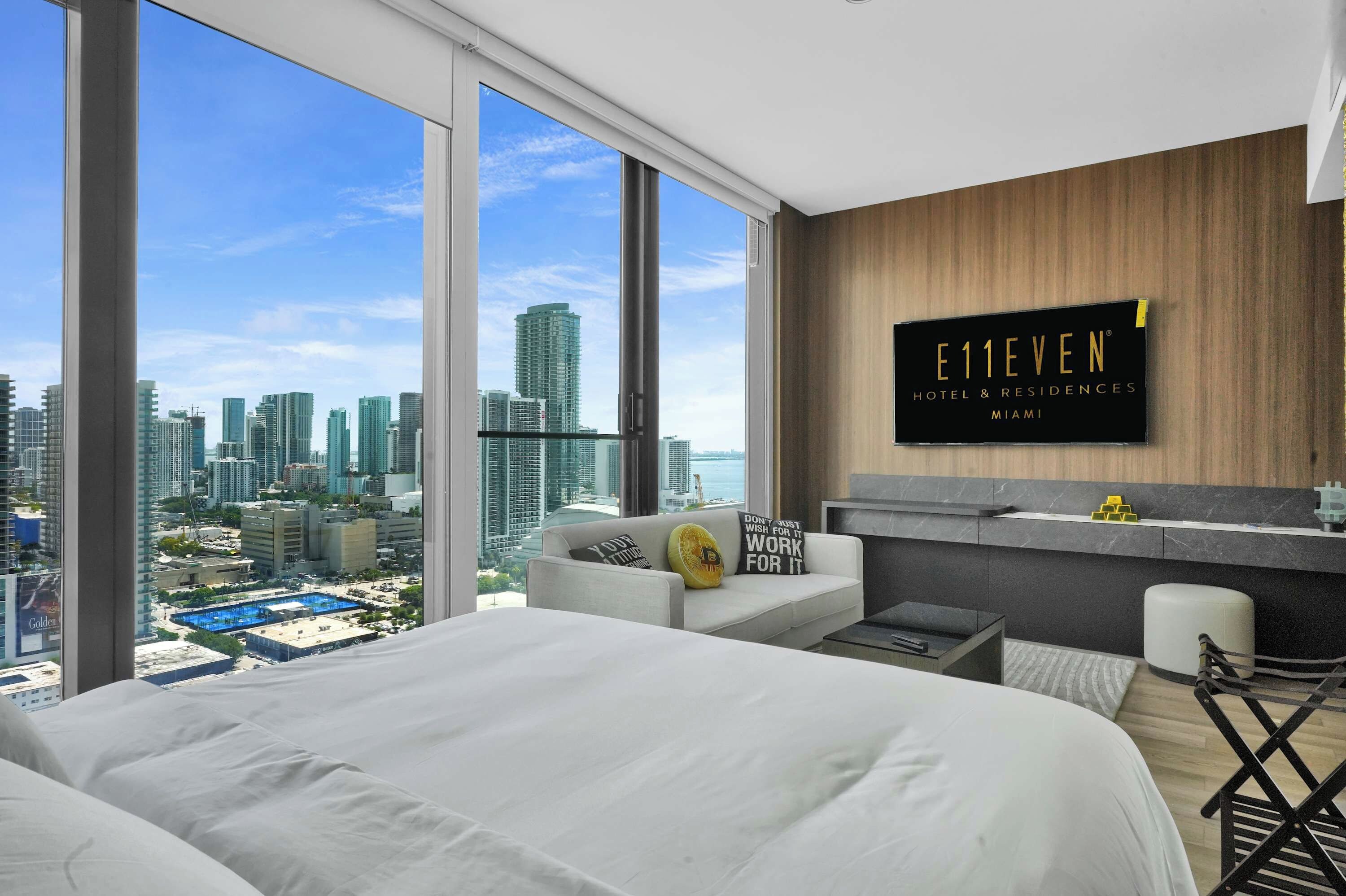 A modern hotel room with a large bed, a seating area, and a city view.