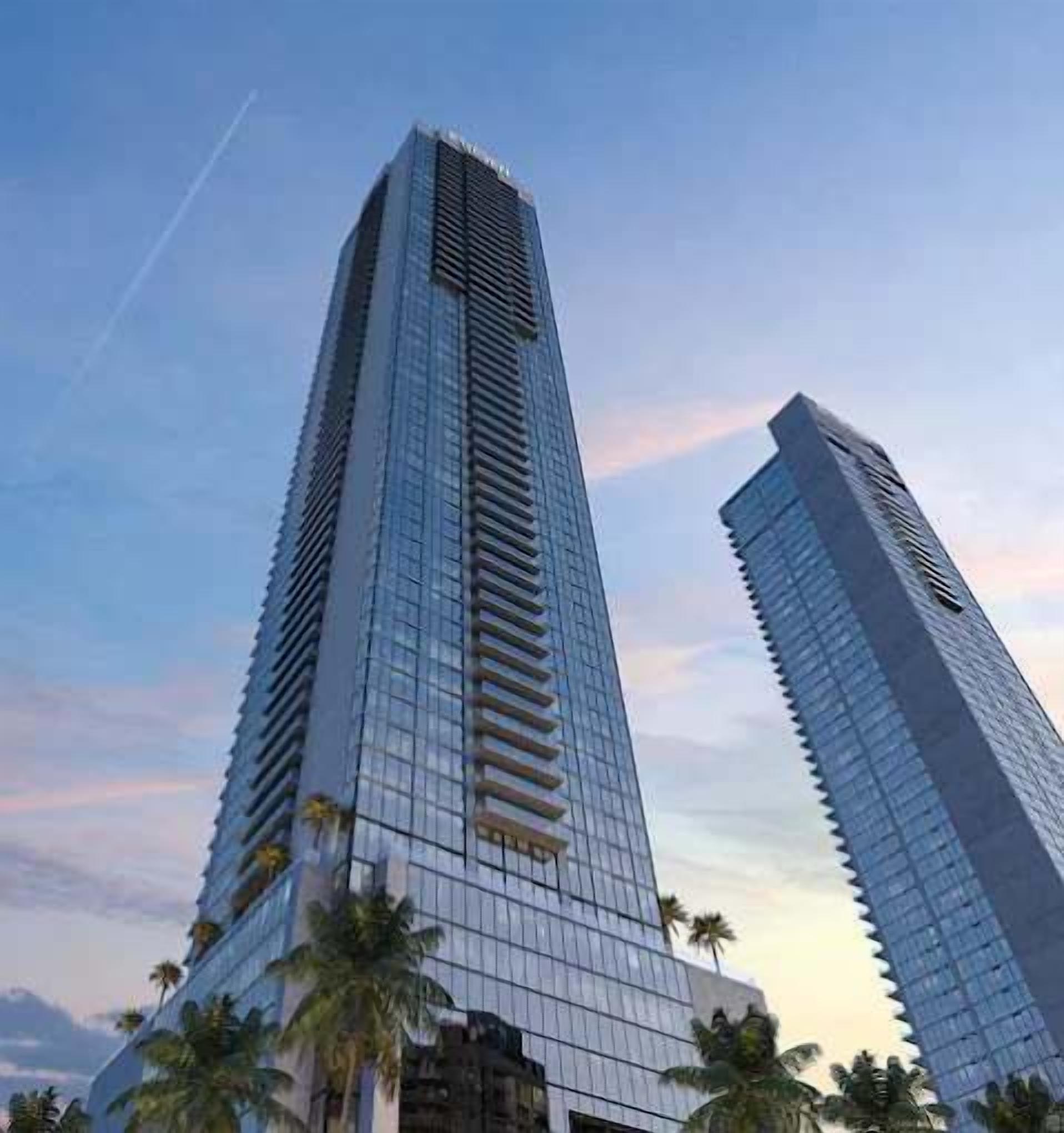 Two tall, modern skyscrapers with reflective glass facades and a clear sky in the background.