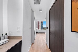 A hotel hallway with a bed, a bathroom with a towel, and a door leading to a room with a city view. - Luxury Studio at E11EVEN Residences Rooftop Pool (Miami)