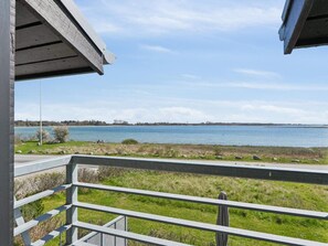 A balcony with a view of a calm lake and distant shoreline. - 4 Star Holiday Home in Martofte (Martofte)