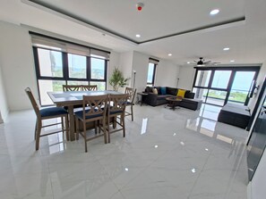 A modern living room with a dining area, large windows, and a ceiling fan. - New/Top Road/Gated/AC/Wi-fi/TV/Pool/Sea view/Gym (Montego Bay)