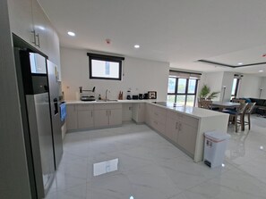 A modern kitchen with a built-in oven, a sink, and a dining area with a table and chairs. - New/Top Road/Gated/AC/Wi-fi/TV/Pool/Sea view/Gym (Montego Bay)