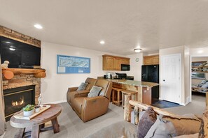 Ein gemütliches Wohnzimmer mit Kamin, einer bequemen Couch und einem Fernseher.