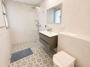 A bathroom with a shower, a sink, a toilet, and patterned floor tiles. - Port city haifa - Sea front 1 bdrm apt w/ mamad (Haifa)