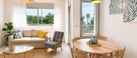 A modern living room with a sofa, armchair, coffee table, dining table, and chairs.