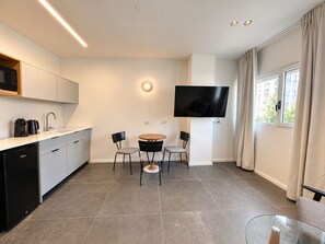 A modern kitchen with a dishwasher, a coffee machine, and a flat-screen TV mounted on the wall. - Port City Haifa - Downtown lux 1 Bedroom 3 (Haifa)