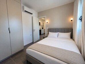 A hotel room with a bed, a wardrobe, an air conditioning unit, a kitchenette, and a bathroom. - Port City Haifa - Downtown lux 1 Bedroom 3 (Haifa)
