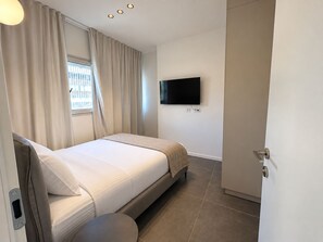 Een hotelkamer met een bed, een aan de muur bevestigde televisie en een deur.
