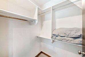 Ein begehbarer Kleiderschrank mit Kleiderstange und Ablage für gefaltete Handtücher.