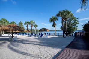 A beach with sun loungers, palm trees, and a wooden deck. - 3BR Disney Gataway/Bahama Bay Resort/Davenport FL (Davenport)