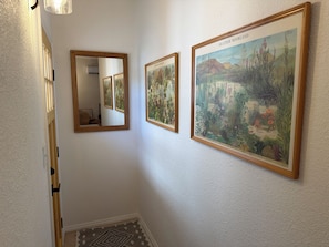 Ein Flur mit einem Spiegel und zwei gerahmten Pflanzenbildern an der Wand.