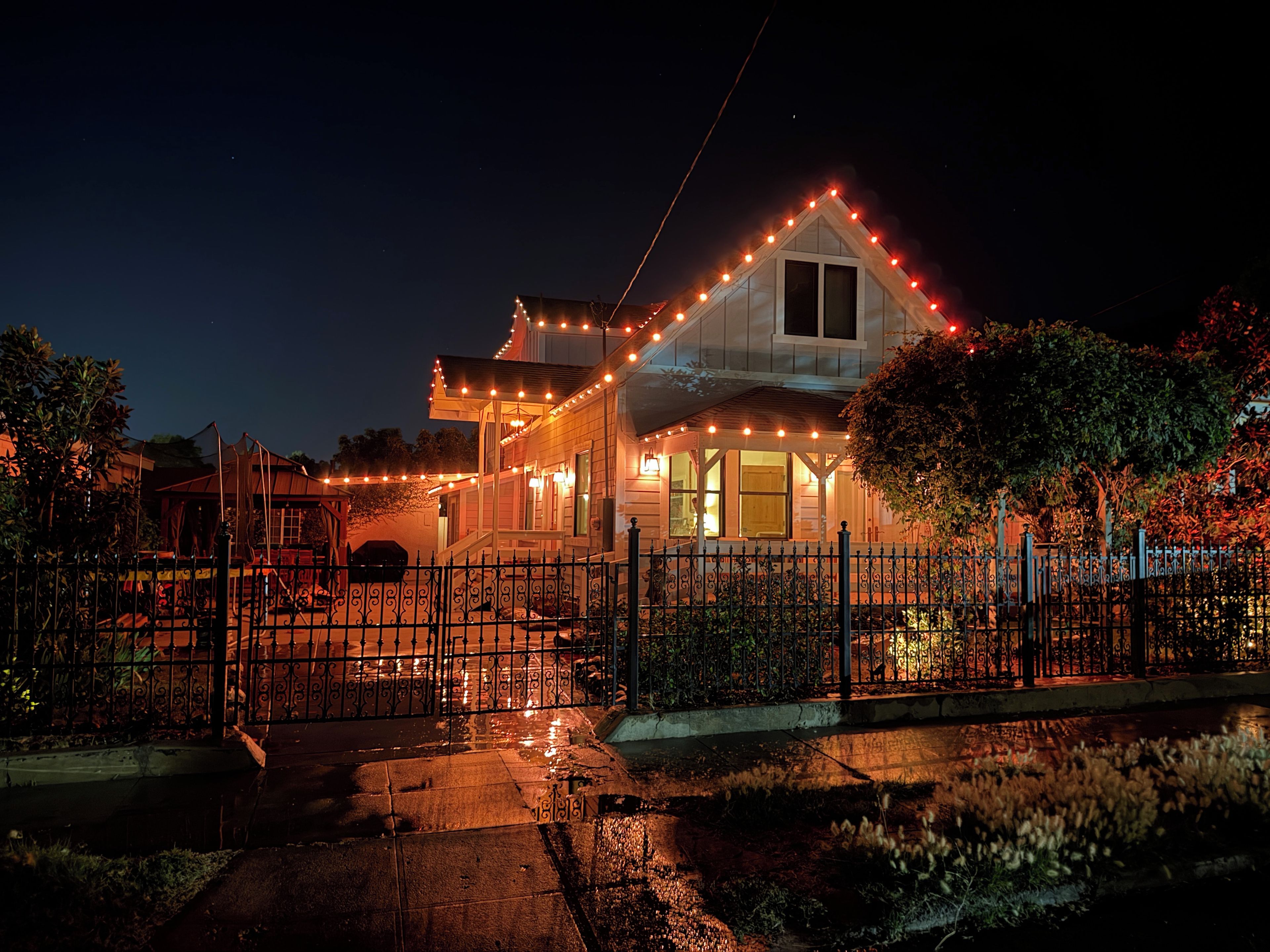 Una casa con porche, cerca y luces colgantes.