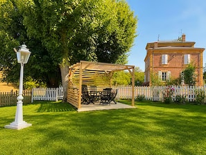 Un kiosque avec des sièges extérieurs, un lampadaire blanc et un bâtiment en briques en arrière-plan.