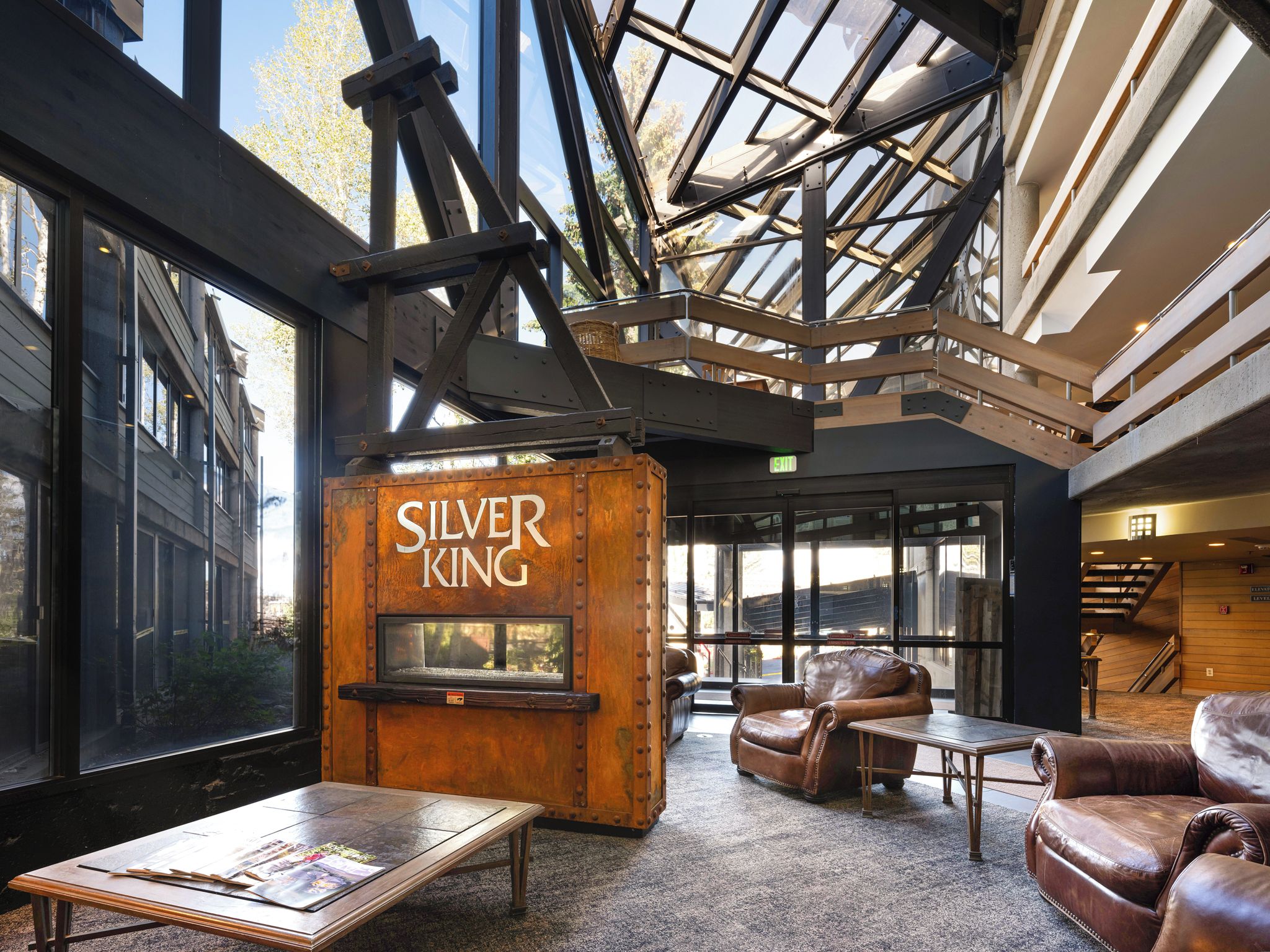 Un hall d’entrée avec une grande enseigne en bois portant l’inscription « SILVER KING », des fauteuils en cuir, une table basse et un plafond haut doté de lucarnes.