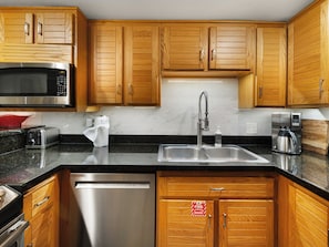 A modern kitchen with wooden cabinets, stainless steel appliances, a microwave, a coffee maker, and a dishwasher. - Ski Access, Bonus Room, Parking Garage, Hot Tub, and Prime Location! (Park City)
