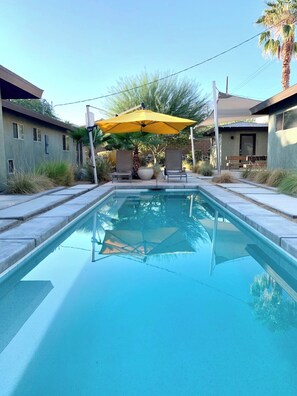 A swimming pool with a yellow umbrella, surrounded by a patio area with chairs and a table. - ENSENADA - Modern, Family-Friendly, Private Pool, Golfer's Paradise (La Quinta)