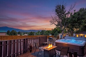 Een terras met een vuurplaats, een jacuzzi en uitzicht op verre bergen.