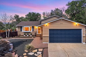 A single-story house with a garage, a front porch, and a well-maintained garden. - Pikes Peak Retreat | Hot Tub, Firepit + Pets (Colorado Springs)