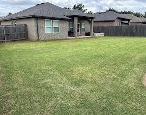 A residential property with a well-maintained lawn, a brick exterior, and a wooden fence. - Charming 3-bedroom house in peaceful neighborhood just 4 miles from OSU campus (Stillwater)