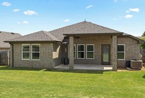 A two-story residential building with a brick exterior, a front porch, and a small attached garage. - Charming 3-bedroom house in peaceful neighborhood just 4 miles from OSU campus (Stillwater)